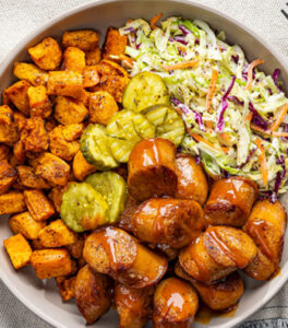 A fresh barbecue bowl of Al Fresco chicken sausage, pickles, slaw, and sweet potato
