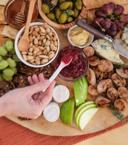 A charcuterie board featuring Al Fresco Sweet Apple Chicken Sausage, grapes, nuts, cheeses